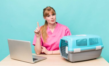 Kızıl saçlı güzel kadın gülümsüyor ve arkadaş canlısı görünüyor, bir numarayı gösteriyor. Veterinerlik kavramı