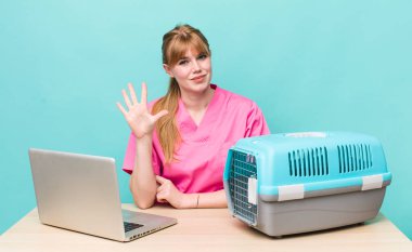 Kızıl saçlı güzel kadın gülümsüyor ve arkadaş canlısı görünüyor, beş numarayı gösteriyor. Veterinerlik kavramı