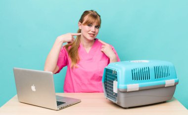 Kızıl saçlı, güzel bir kadın kendi gülüşünü işaret ediyor. Veterinerlik kavramı