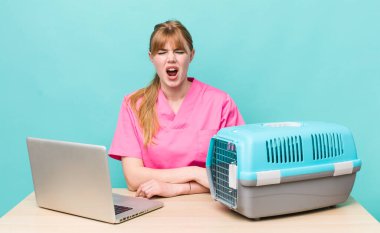 Kızıl saçlı, güzel bir kadın agresif bir şekilde bağırıyor, çok kızgın görünüyor. Veterinerlik kavramı