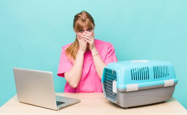 Kızıl saçlı, güzel bir kadın elleri ile ağzını kapatıyor. Veterinerlik kavramı