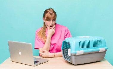 Kızıl saçlı, ağzı ve gözleri açık, eli çenesinde güzel bir kadın. Veterinerlik kavramı