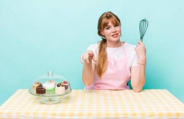 Kızıl saçlı güzel kadın kamerayı işaret ederek seni seçiyor. Ev yapımı kek konsepti