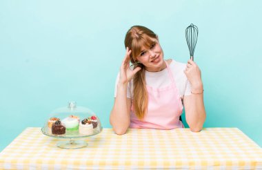 Kızıl saçlı güzel kadın stresli, endişeli ya da korkmuş, elleri başının üstünde. Ev yapımı kek konsepti