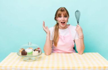 Kızıl saçlı güzel kadın kendini mutlu hissediyor ve inanılmaz bir şeye hayret ediyor. Ev yapımı kek konsepti