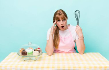 Kızıl saçlı güzel kadın mutlu, şaşkın ve şaşırmış görünüyor. Ev yapımı kek konsepti