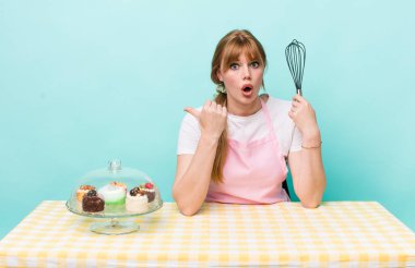 Kızıl saçlı, güzel bir kadın inançsızlıktan şaşkın şaşkın bakıyor. Ev yapımı kek konsepti