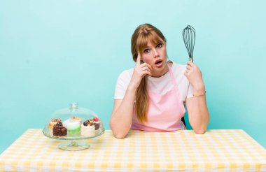 Kızıl saçlı güzel kadın şaşırmış görünüyor, yeni bir düşünce, fikir ya da konsept fark ediyor. Ev yapımı kek konsepti