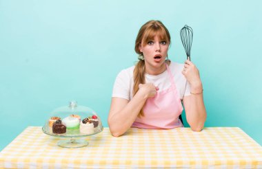 Kızıl saçlı güzel kadın şok olmuş ve ağzı açık, kendini işaret eden bir şekilde şaşırmış görünüyor. Ev yapımı kek konsepti