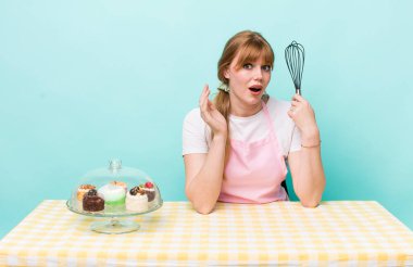 Kızıl saçlı güzel kadın kendini mutlu hissediyor, bir çözüm ya da fikir bulduğuna şaşırıyor. Ev yapımı kek konsepti