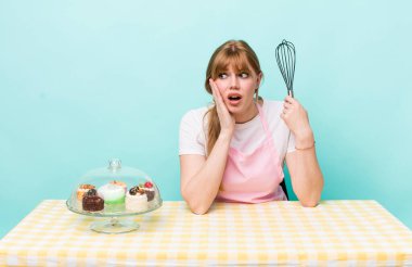 Kızıl saçlı güzel kadın mutlu, heyecanlı ve şaşırmış hissediyor. Ev yapımı kek konsepti