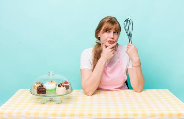 Kızıl saçlı güzel kadın düşünüyor, kuşkulu ve şaşkın hissediyor. Ev yapımı kek konsepti