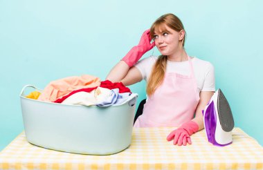 Kızıl saçlı güzel kadın şaşkın ve kafası karışık, kaşınan bir kafa hissediyor. Demir giysi konsepti