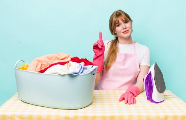 Kızıl saçlı güzel kadın gülümsüyor ve arkadaş canlısı görünüyor, bir numarayı gösteriyor. Demir giysi konsepti