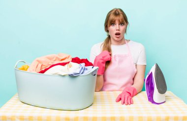 Kızıl saçlı güzel kadın şok olmuş ve ağzı açık, kendini işaret eden bir şekilde şaşırmış görünüyor. Demir giysi konsepti