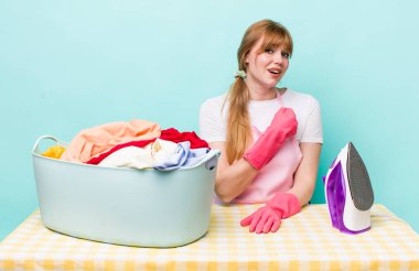 Kızıl saçlı güzel bir kadın kendini mutlu hissediyor ve bir meydan okumayla yüzleşiyor ya da kutluyor. Demir giysi konsepti