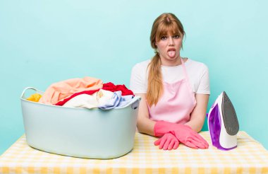 Kızıl saçlı güzel kadın iğrenmiş ve sinirlenmiş hissediyor ve dilini dışarı çıkarıyor. Demir giysi konsepti