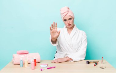 Kızıl saçlı güzel kadın ciddi görünüyor. Avuç içini gösteriyor. Durdurma hareketi yapıyor. duş ve kozmetik konsepti