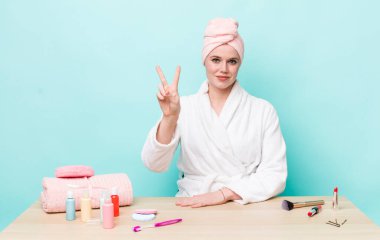 Kızıl saçlı güzel kadın gülümsüyor ve arkadaş canlısı görünüyor, iki numarayı gösteriyor. duş ve kozmetik konsepti