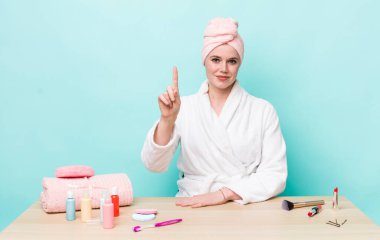 Kızıl saçlı güzel kadın gülümsüyor ve arkadaş canlısı görünüyor, bir numarayı gösteriyor. duş ve kozmetik konsepti