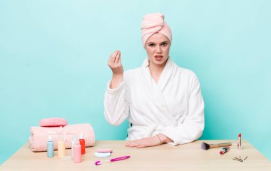 Kızıl saçlı, güzel bir kadın kapiş ya da para hareketi yapıyor, sana ödemeni söylüyor. duş ve kozmetik konsepti