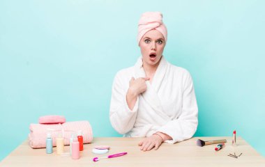 Kızıl saçlı güzel kadın şok olmuş ve ağzı açık, kendini işaret eden bir şekilde şaşırmış görünüyor. duş ve kozmetik konsepti