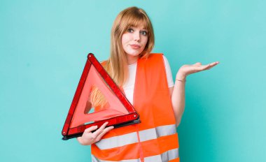 Kızıl saçlı güzel kadın şaşkın, şaşkın ve şüpheci hissediyor. araba acil üçgeni