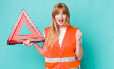 Kızıl saçlı güzel kadın şok olmuş hissediyor, gülüyor ve başarıyı kutluyor. araba acil üçgeni