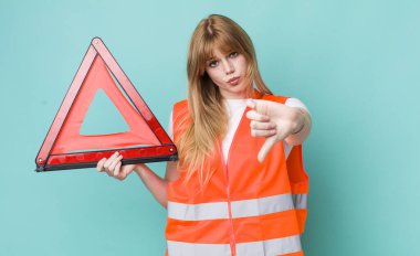 Kızıl saçlı, güzel bir kadın kendini kötü hissediyor, baş parmağını kaldırıyor. araba acil üçgeni