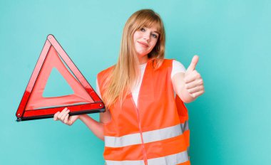 Kızıl saçlı güzel bir kadın gururlu, olumlu gülümsüyor. araba acil üçgeni