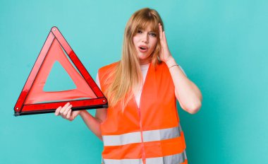 Kızıl saçlı güzel kadın mutlu, şaşkın ve şaşırmış görünüyor. araba acil üçgeni