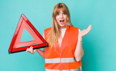 Kızıl saçlı güzel kadın kendini mutlu hissediyor ve inanılmaz bir şeye hayret ediyor. araba acil üçgeni