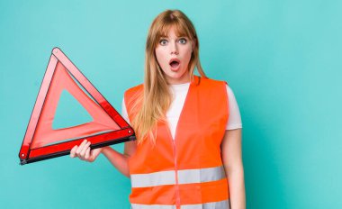 Kızıl saçlı güzel kadın çok şaşırmış ya da şaşkın görünüyor. araba acil üçgeni