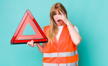 Kızıl saçlı güzel bir kadın şok olmuş, korkmuş ya da korkmuş görünüyor. araba acil üçgeni