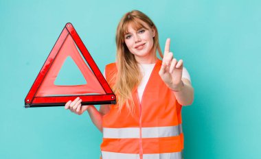 Kızıl saçlı güzel kadın gururla gülümsüyor ve kendinden emin bir numara oluyor. araba acil üçgeni