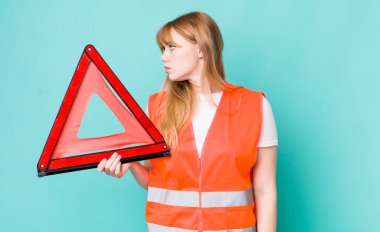 Profil bakışlı kızıl saçlı güzel kadın hayal mi kuruyor yoksa hayal mi kuruyor? araba acil üçgeni