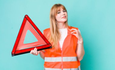 Kızıl saçlı güzel kadın kibirli, başarılı, pozitif ve gururlu görünüyor. araba acil üçgeni