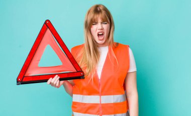 Kızıl saçlı, güzel bir kadın agresif bir şekilde bağırıyor, çok kızgın görünüyor. araba acil üçgeni