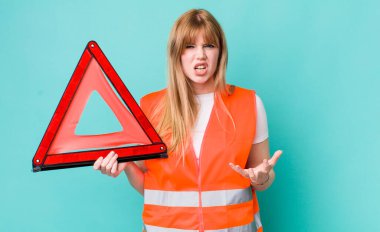 Kızıl saçlı, güzel bir kadın sinirli, sinirli ve sinirli görünüyor. araba acil üçgeni