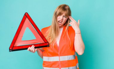 Kızıl saçlı güzel bir kadın mutsuz ve stresli görünüyor, intihar jesti silah işareti yapıyor. araba acil üçgeni