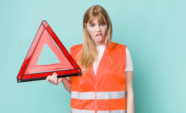 Kızıl saçlı güzel kadın iğrenmiş ve sinirlenmiş hissediyor ve dilini dışarı çıkarıyor. araba acil üçgeni