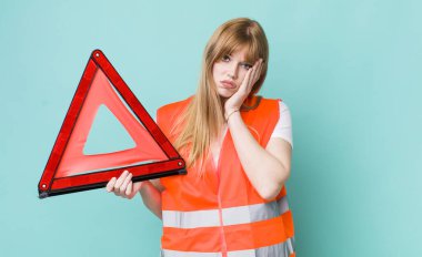 Kızıl saçlı, güzel bir kadın bıkkın, yorgun ve uykulu hissediyor. araba acil üçgeni