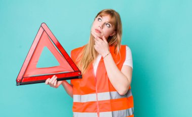 Kızıl saçlı güzel kadın düşünüyor, kuşkulu ve şaşkın hissediyor. araba acil üçgeni