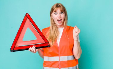 Kızıl saçlı güzel bir kadın sinirli bir ifadeyle agresif bir şekilde bağırıyor. araba acil üçgeni