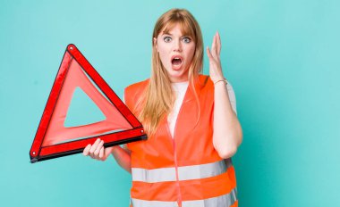 Kızıl saçlı güzel kadın ellerini havaya kaldırarak çığlık atıyor. araba acil üçgeni