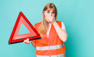 Kızıl saçlı, güzel bir kadın elleri ile ağzını kapatıyor. araba acil üçgeni