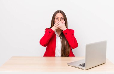 İspanyol asıllı güzel bir kadın elleri ile ağzını kapatıyor. iş ve masa konsepti