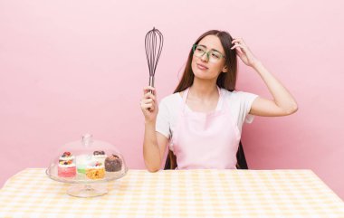 İspanyol güzel kadın şaşkın ve kafası karışık, kaşınan bir kafa hissediyor. Ev yapımı kek konsepti