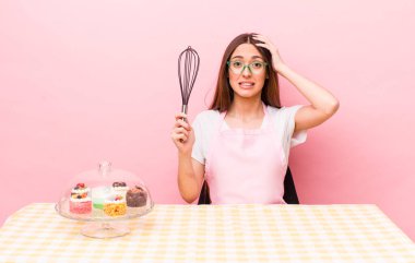 İspanyol güzel kadın kendini stresli, endişeli ya da korkmuş hissediyor, elleri başının üstünde. Ev yapımı kek konsepti