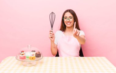 Hispanik güzel kadın gururla gülümsüyor ve kendinden emin bir numara oluyor. Ev yapımı kek konsepti